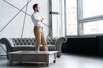 Looking perfect. Full length of handsome young man looking away while standing at home.