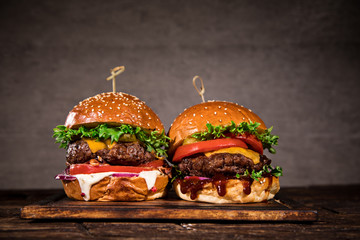 Tasty burgers on wooden table.