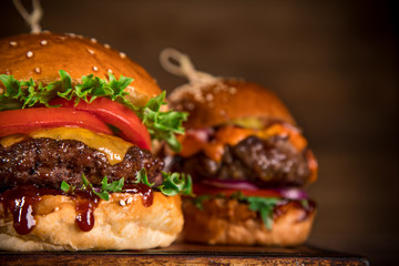Tasty burgers on wooden table.