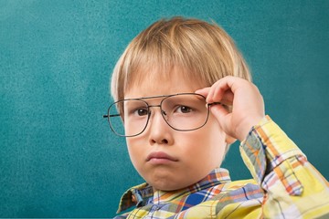 Cute little schoolgirl in glasses on blackboard background