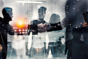 Naklejka premium Handshaking business person in office. concept of teamwork and partnership. double exposure