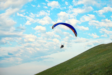 Trike with a parachute against the blue sky. Paragliding flying over the clouds
