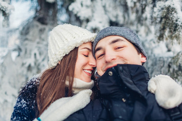 Fototapeta premium Couple in love taking selfie and hugging in winter forest. Young happy people having fun. Valentine's day