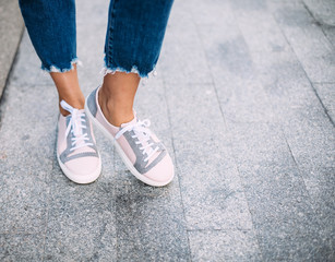 Woman with stylish shoes in the city.Closeup of legs and sneakers
