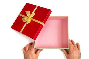 Open gift box with gold ribbon bow in men's hands, isolated on white