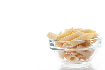 Raw feathers macaroni in bowl. Italian pasta close up, isolated on the white background