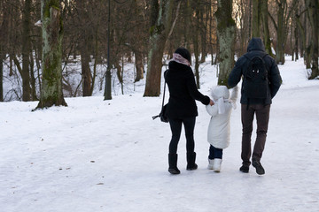 Fototapeta na wymiar Happy family is walking in snowy park in winter sunny day. Concept of love, happiness, support. childhood, desires.