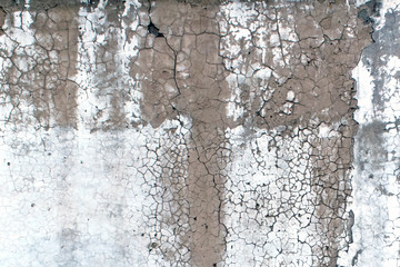 Obraz premium Extreme distressed peeling white painted wall with mud. vintage background texture the ancient cement with cracks. Pieces of old peeling paint with cracks over concrete surface. Material