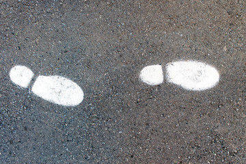 traces of shoes on the asphalt with white paint. footprints on the road, top view, background texture 