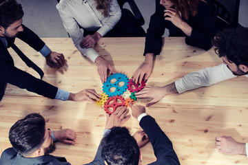 Business team connect pieces of gears. Photo from above. Teamwork, partnership and integration...
