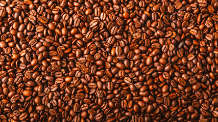 Roasted coffee beans spread over an entire surface