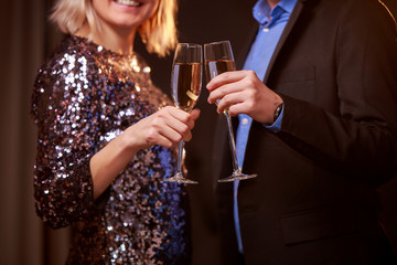 Photo of blonde woman in brilliant dress and men with wine glasses with champagne on black background