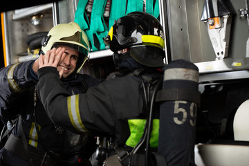 Image of two firemen men making handshake near fire truck