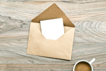 Envelope and coffee with empty paper on wooden table 