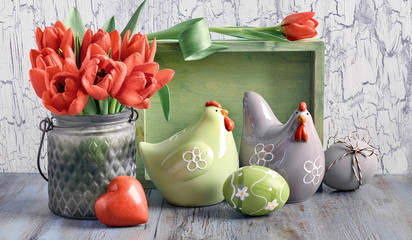 Easter composition with red tulips, ceramic hens and Easter eggs on light wood