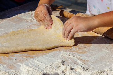 Woman's hands rolling out a dough with rolling pin