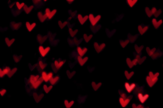 Red heart valentine bokeh lights against a black background
