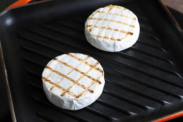Tasty chequered camembert cheese frying on cast iron grill pan. Fresh grillde brie cheese