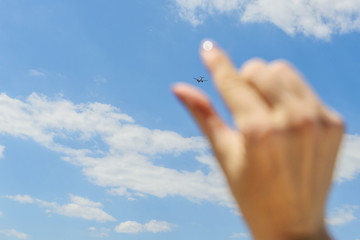 female hand holding an airplane flying in the sky