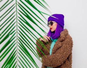 Beautiful young girl with purple hair in jacket with palm leaf on white background.
