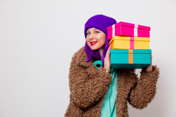 Beautiful young girl with purple hair in jacket with holiday gift boxes on white background.