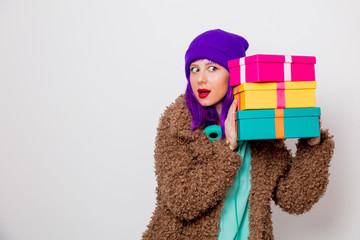 Beautiful young girl with purple hair in jacket with holiday gift boxes on white background.