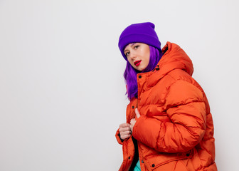 Beautiful young girl with purple hair and in orange jacket on white background.