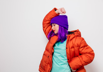 Beautiful young girl with purple hair and in orange jacket on white background.