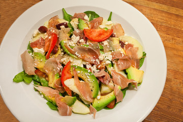 Mixed summer salad with avocado, ham and tomato