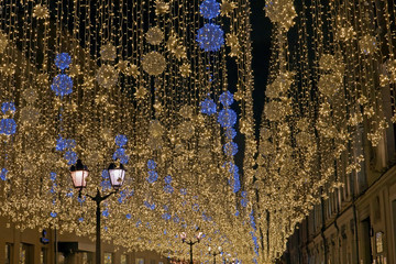 Street decoration in winter in snowfall. Street of the big city decorated for the holiday with hanging garlands.
