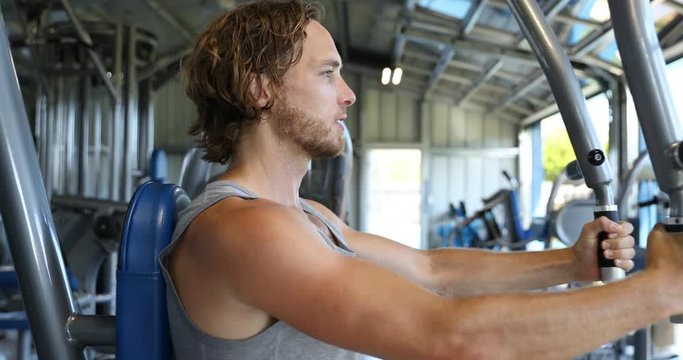 Man at fitness gym. Man doing butterfly chest workout on fitness machine at gym. Athlete working out chest muscles doing strength training exercises on gym chest fly machine equipment. REAL TIME.
