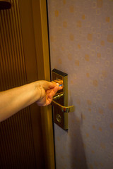 hand inserting a key card into a hotel room electronic door security lock to unlock the door