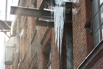 Icicles hanging from roof of the building/copy space/dangerous situation, сold winter, severe winter, poor thermal insulation, ice stalactite, formation of icicles, frost and winter weather concept.
