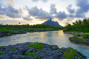 Sunset view of the Mont Otemanu mountain reflecting in water over the reef between the ocean and the lagoon in Bora Bora, French Polynesia, South Pacific - obrazy, fototapety, plakaty