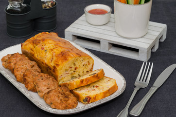 Tray of appetizers meatballs and savory bread with bell pepper, herbs, cheese and olives. Rustic style. 