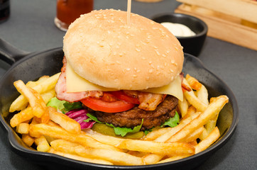 Homemade delicious hamburger served with french fries and sauce. Homemade cheeseburger. 