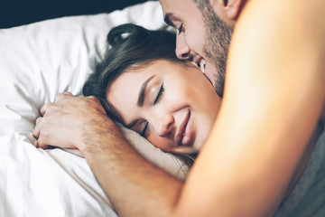 Happy romantic couple having a tender moment in the bed - Young passionate lover waking up in the...