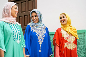 Happy muslim women walking in the city - Arabian teen girls having fun outdoor - concept of people,...