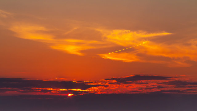 sky during a colorful, bright orange sunset, sun's rays make their way through the clouds © Галина Сандалова