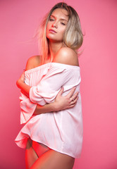 young sensuality blonde   girl in white blouse is standing on pink wall background, glamour concept, embrace and relax