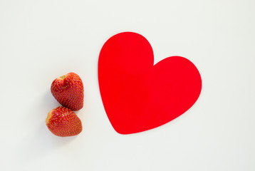 Valentine's Day-two ripe red strawberries with a red paper heart isolated on white