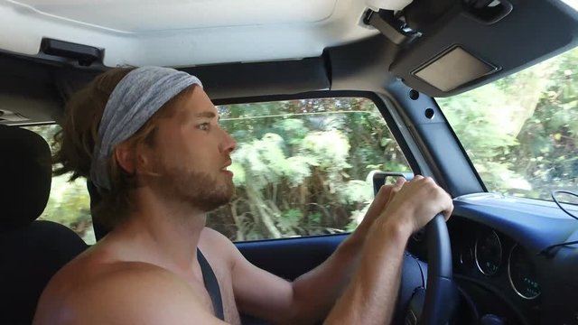 Man driving car on bumpy dirt road on adventure road trip. Shirtless man on exploration travel in 4 wheel drive.