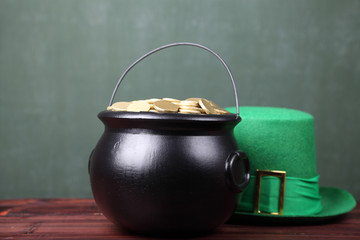 Leprechaun's cauldron full of gold and a green hat on a table