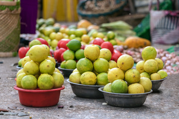 Group of fresh green and yellow lemons placed on baskets on the floor at the street market of Toliara, Madagascar.