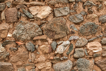 Old grunge weathered stone wall of rural farm house closeup as background
