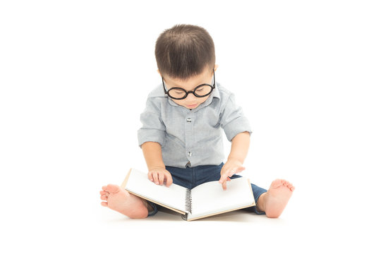 Cute little child play with book and wearing glasses while sitting on floor isolated over white background, Asian baby boy and education concept