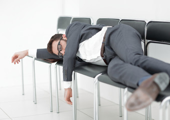 tired businessman lying on chairs and waiting for an interview