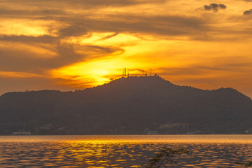 The background of the trees that stand on the lake or in the natural water source behind the mountains is surrounded and has a beautiful evening sky light, seen during travel.