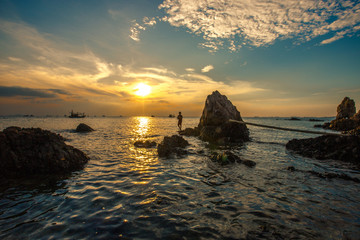 The background of the sea by the evening sea, with natural beauty (sea water, rocks, sky) and fishermen are fishing by the river bank, is a pleasure during travel.