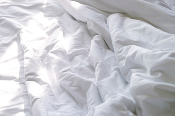 Top view of white unmade bedsheet on a bed in bedroom with beautiful sunlight